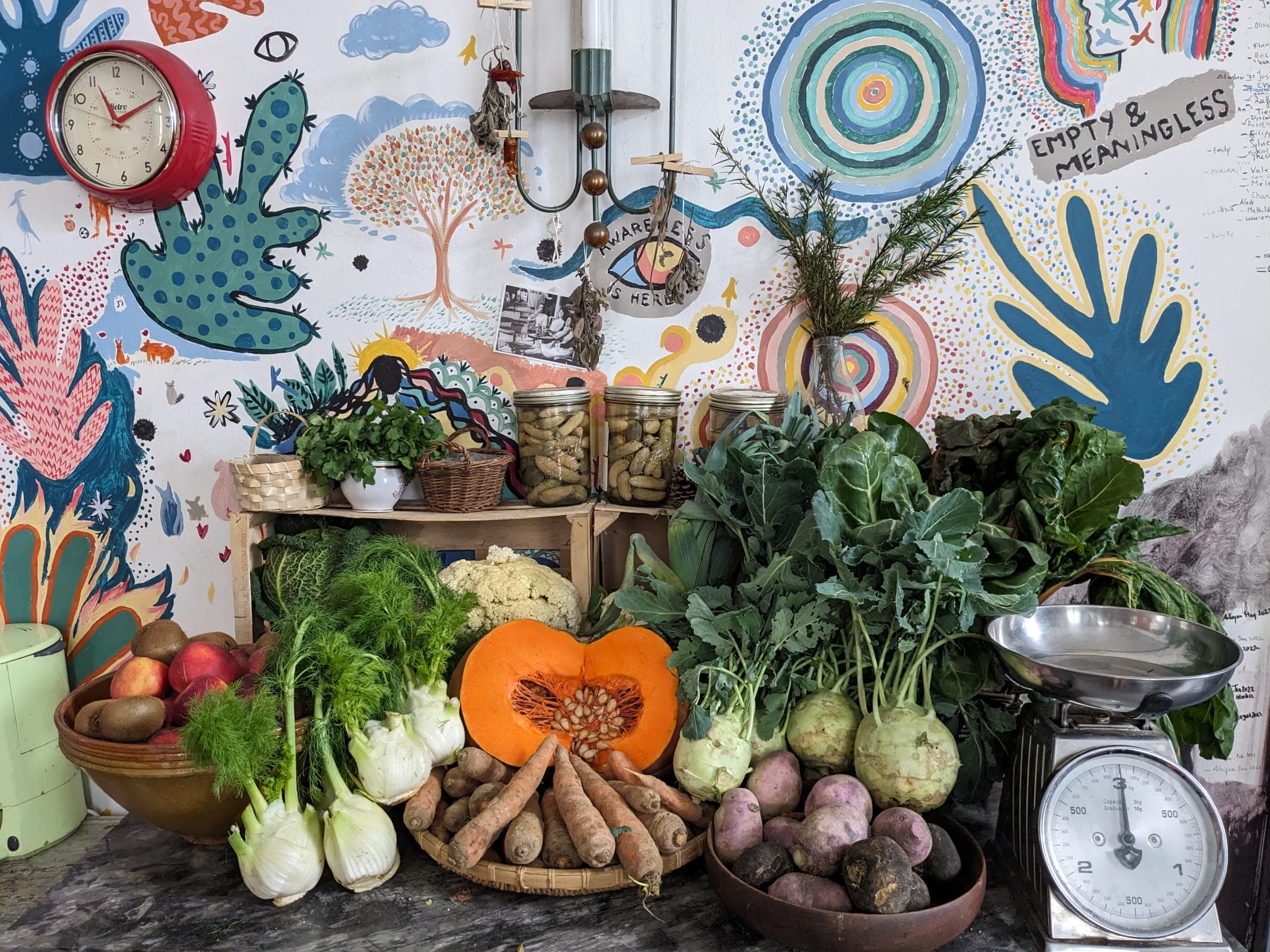 Seasonal produce arranged against the hand-painted mural wall at the hub