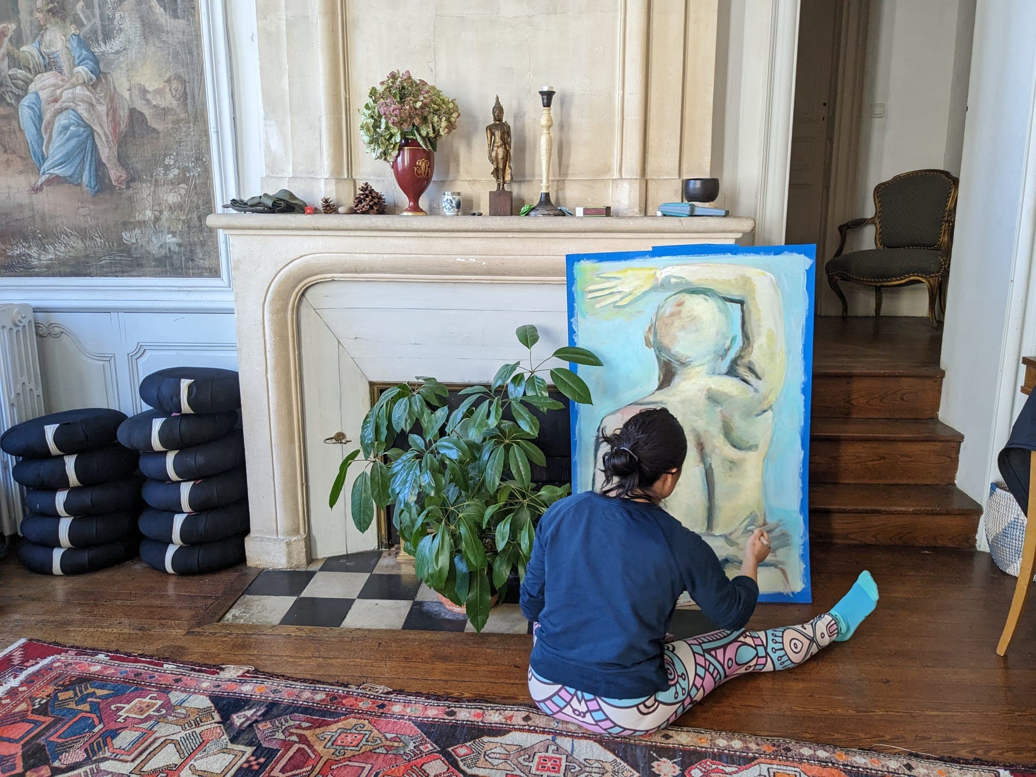 A resident painting a large canvas by the fireplace